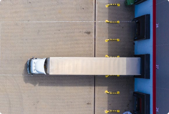 A semi-truck backs into a loading dock